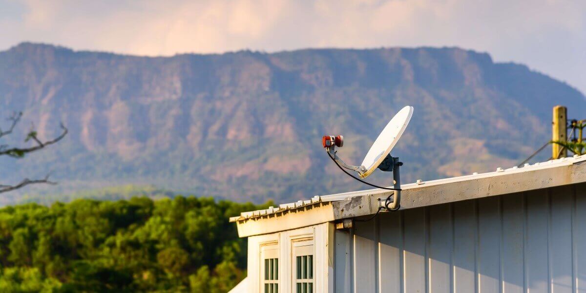 satellite dish on roof of house in rural area next to mountain