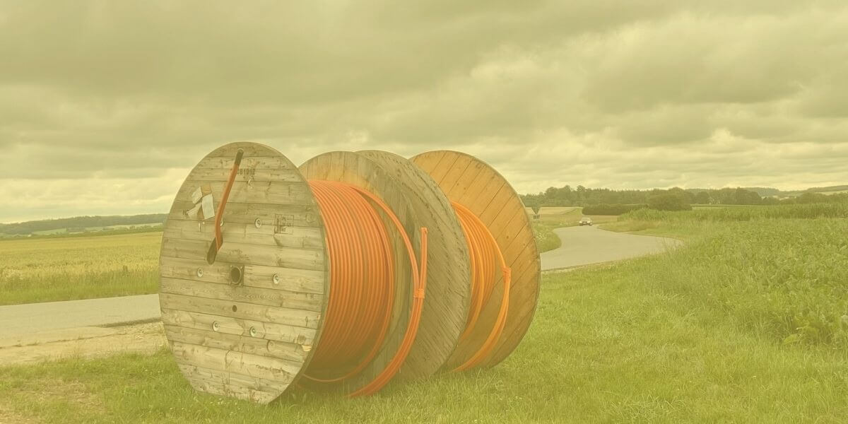 un rollo de líneas de fibra óptica junto a una carretera rural