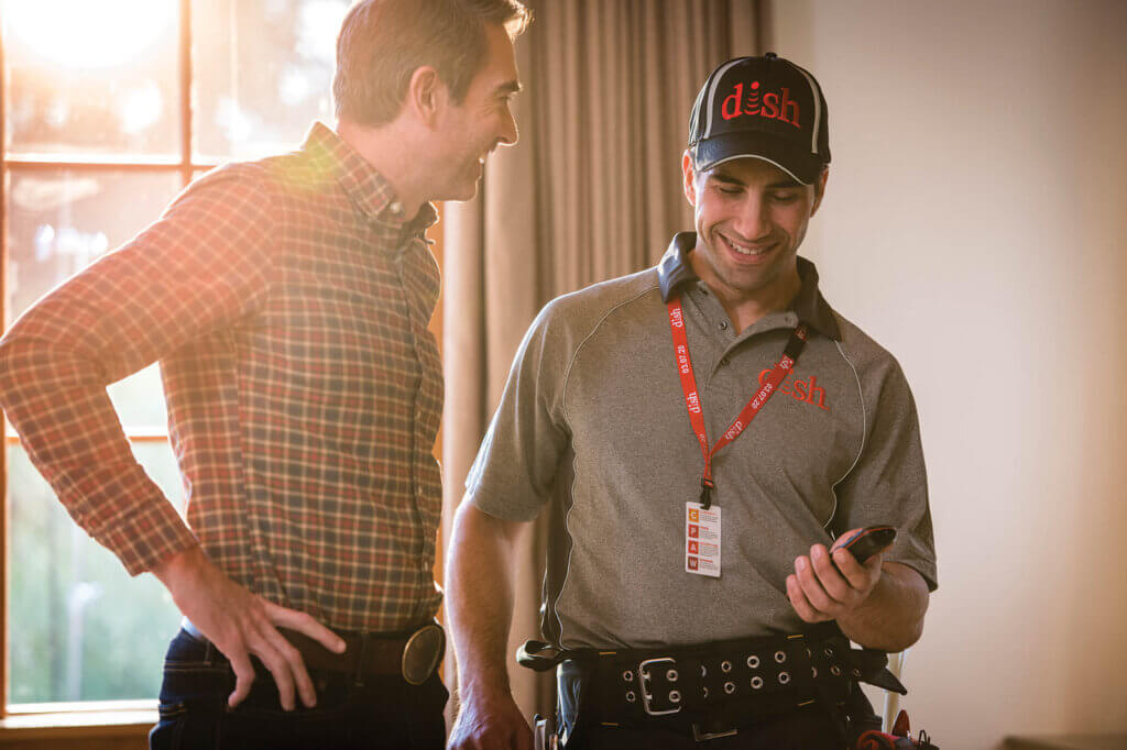 dish technician holding a remote control while speaking to a man