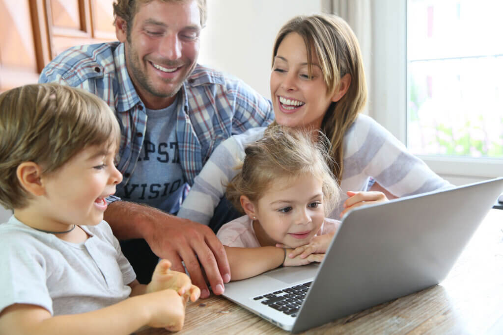 mother and father with their two children using a laptop computer at home