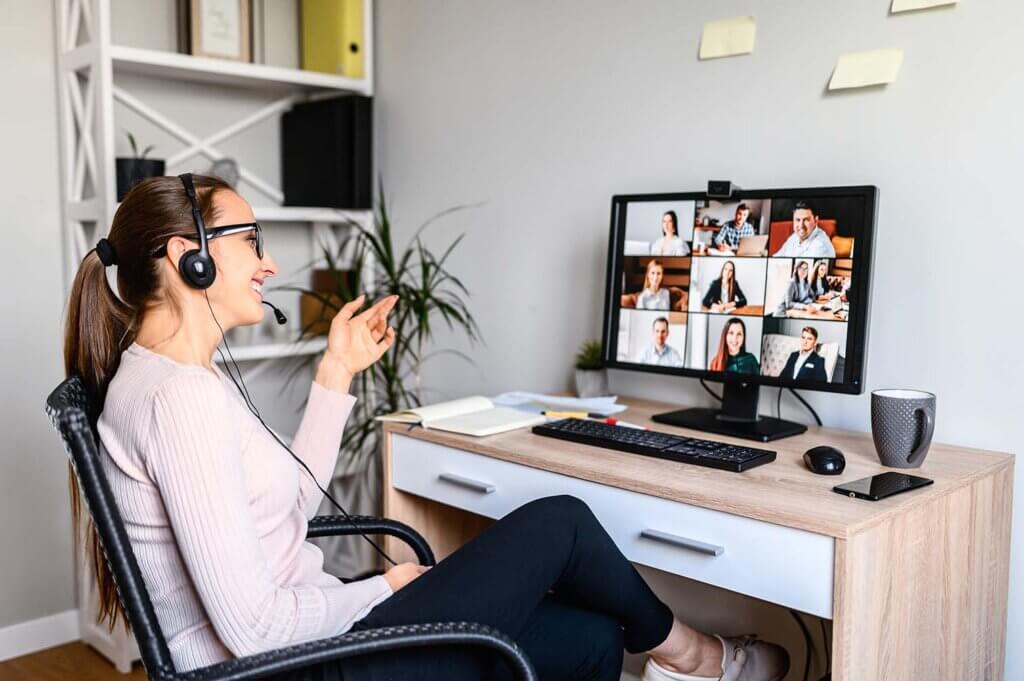 Women sitting at desk with headphones while participating in a virtual meeting
