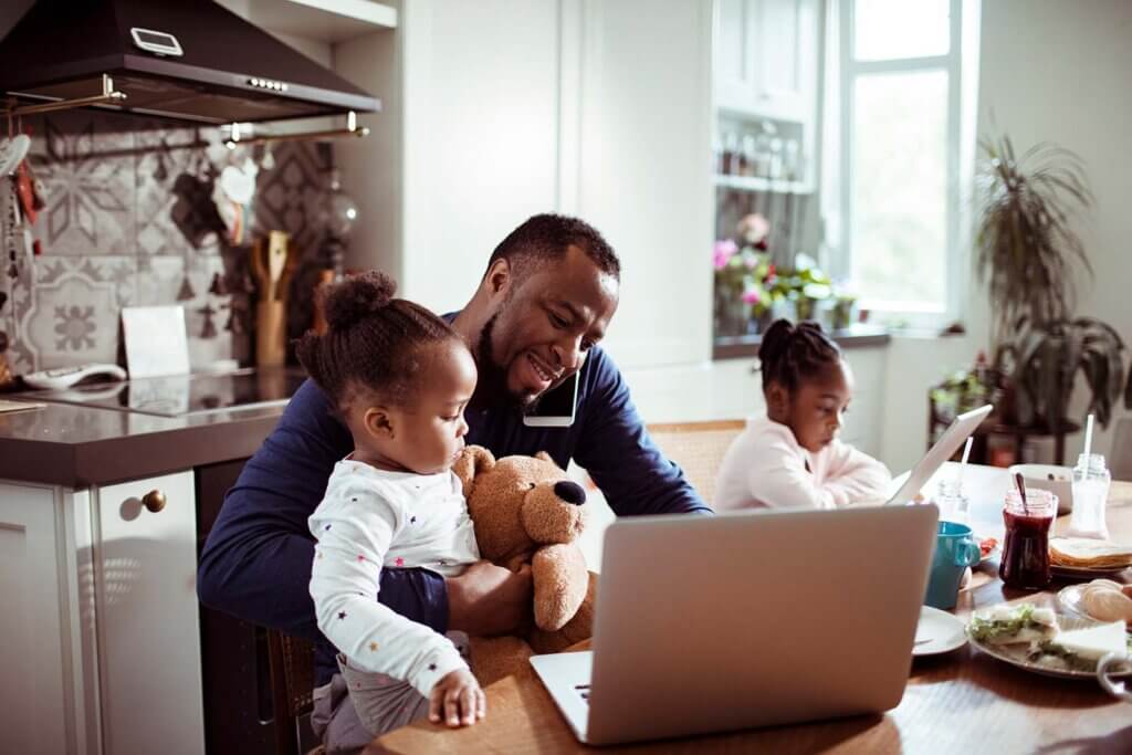 father and his two children working on his laptop at home