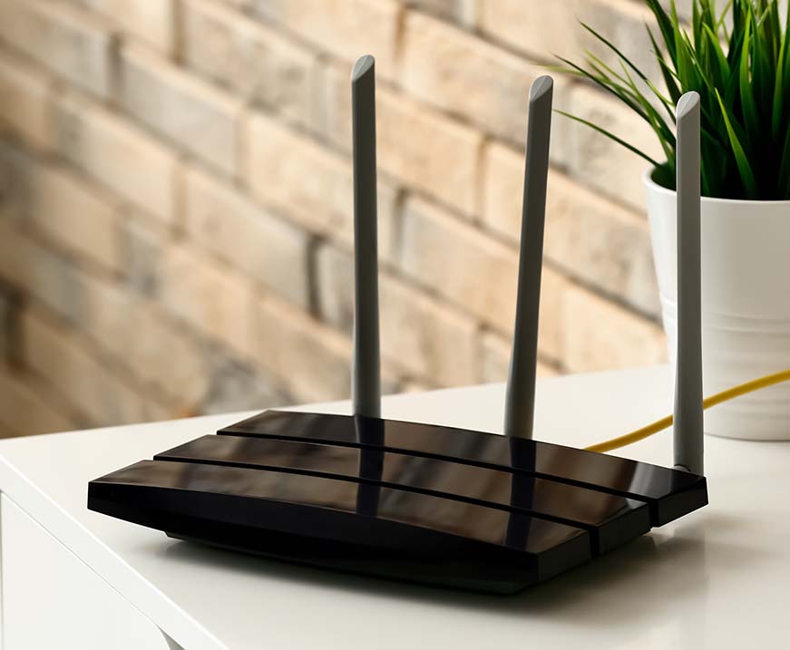 A black router on a table with three antennas 