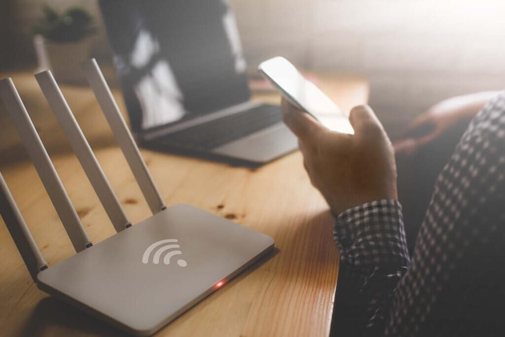man holding a phone near a wifi router