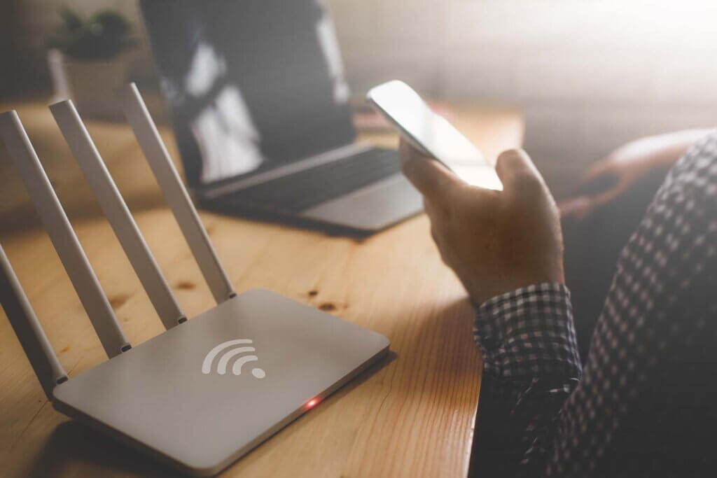 hombre sosteniendo un teléfono cerca de un router wifi