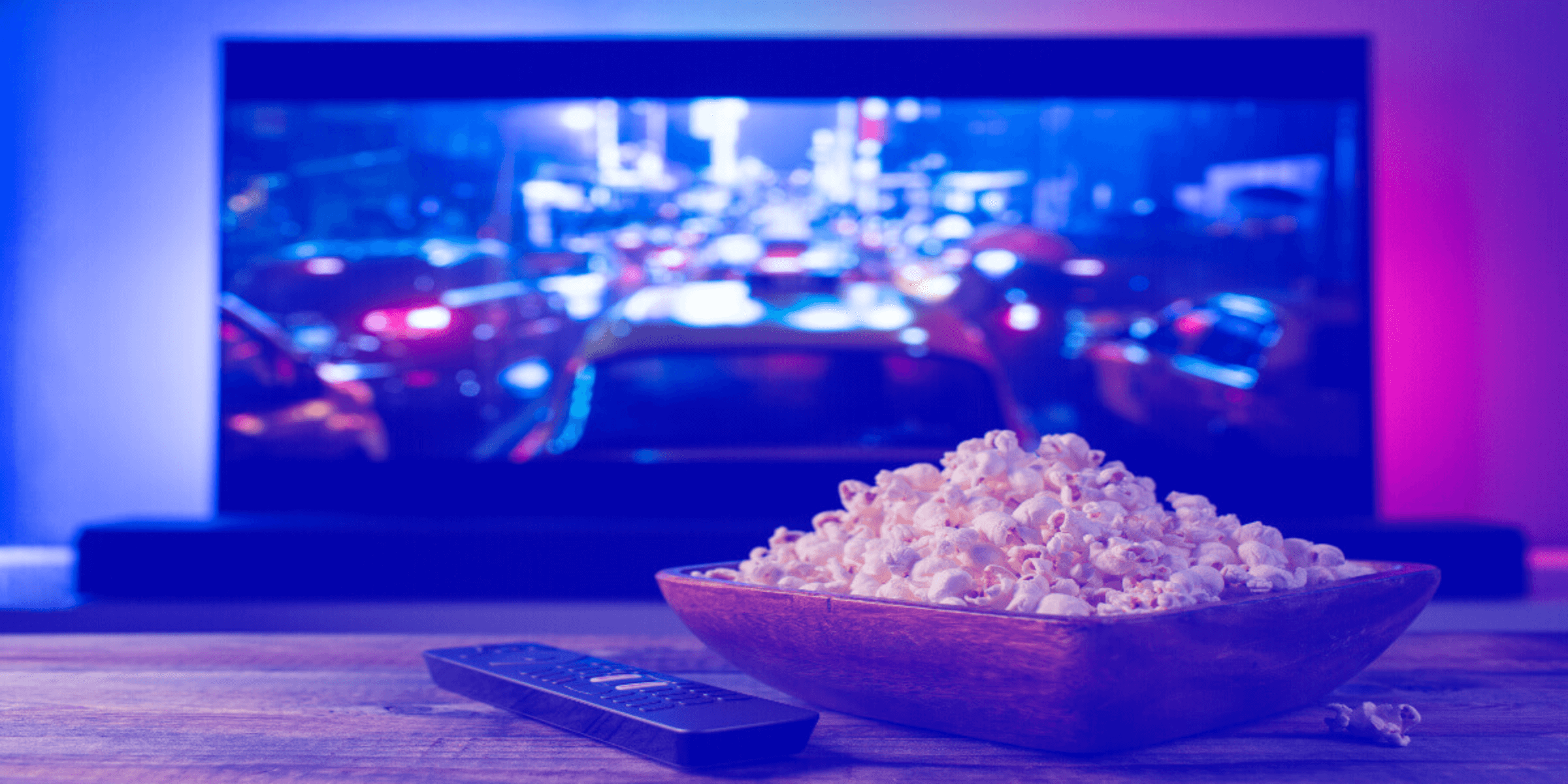 Televisión encendido y popcorn en la mesa.