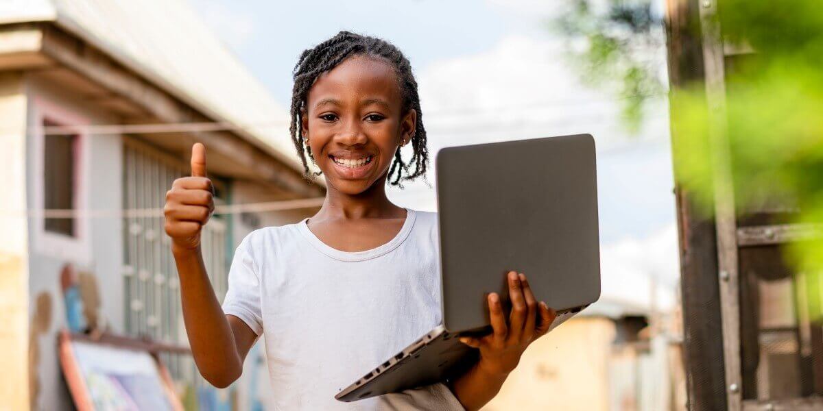 Una joven negra sonríe mientras usa su tableta en la calle