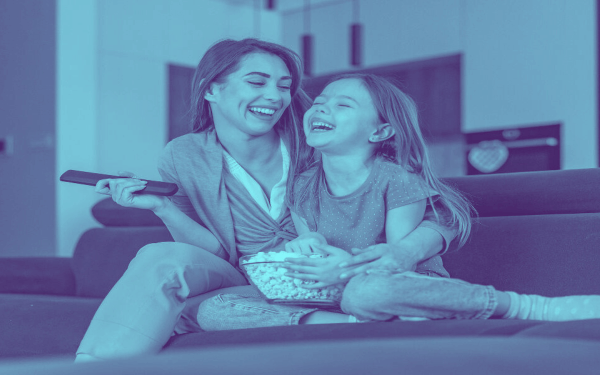 Mom and daughter laughing while watching TV