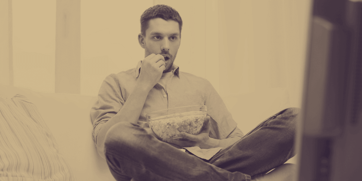 Man eating popcorn while watching TV