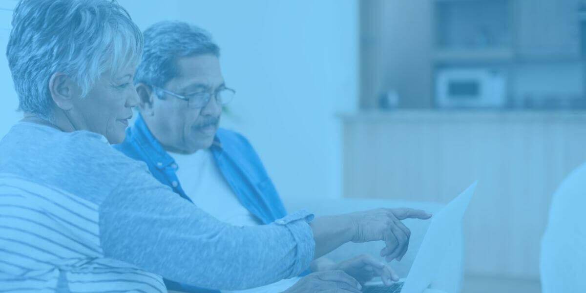 Elderly couple sits at laptop using their ACP program benefit