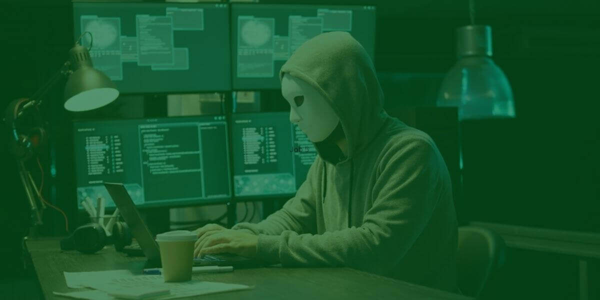 Online scammer is a man in a mask using a computer in a control center