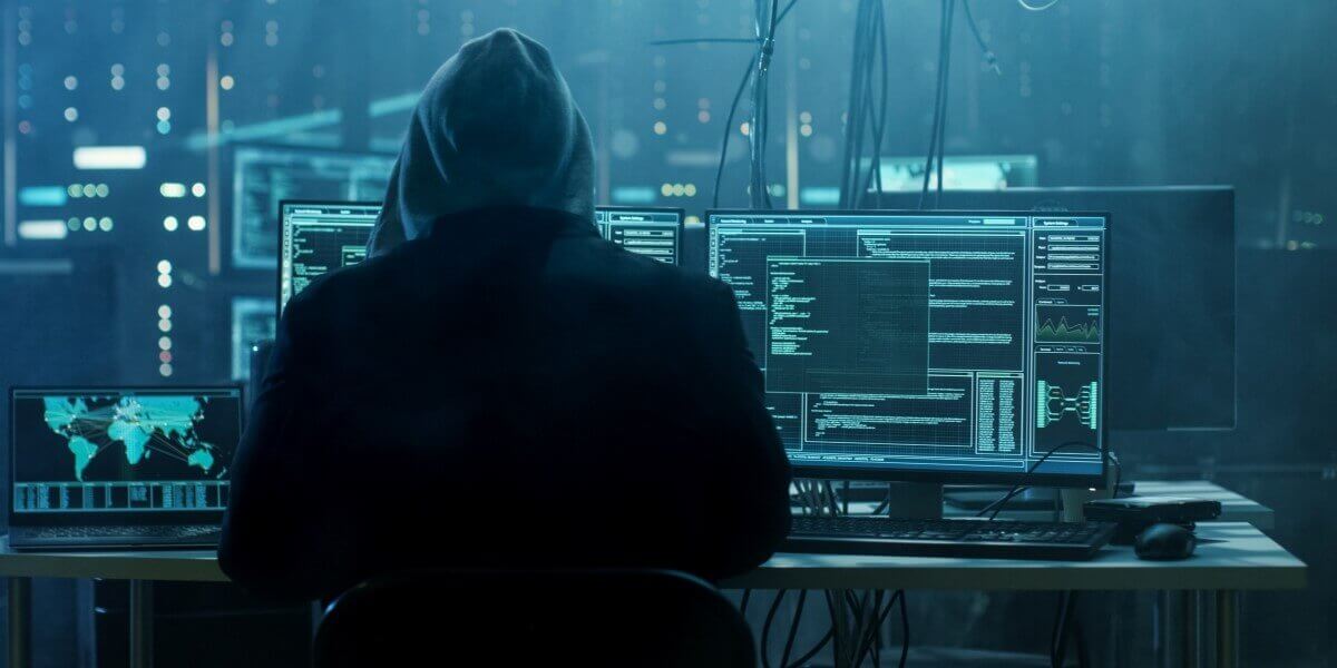 hacker sits at monitors conducting a cyberattack