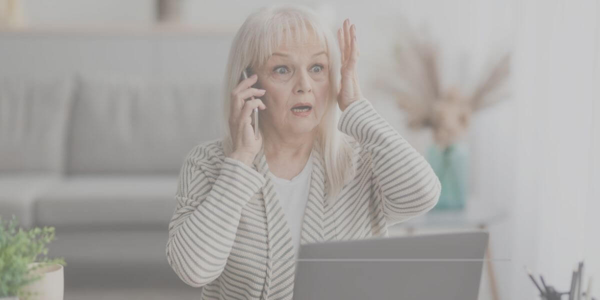 Mature woman looks dismayed about online scams as she uses her laptop