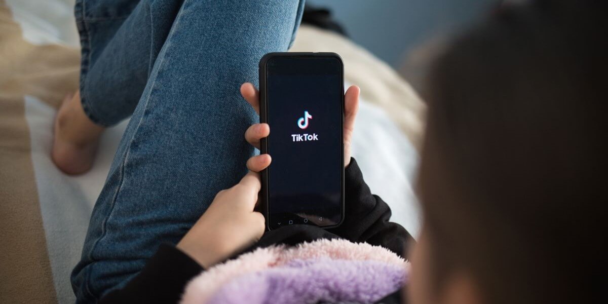 TikTok user holds phone in lap with TikTok logo