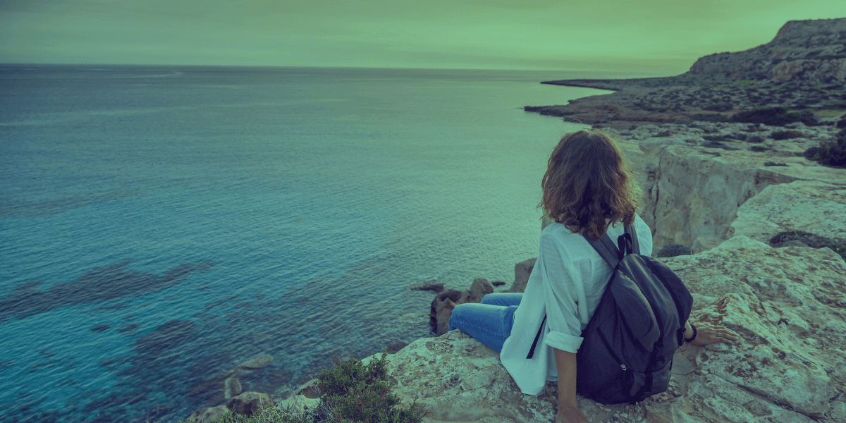 Viajera se sienta en un acantilado mirando el mar