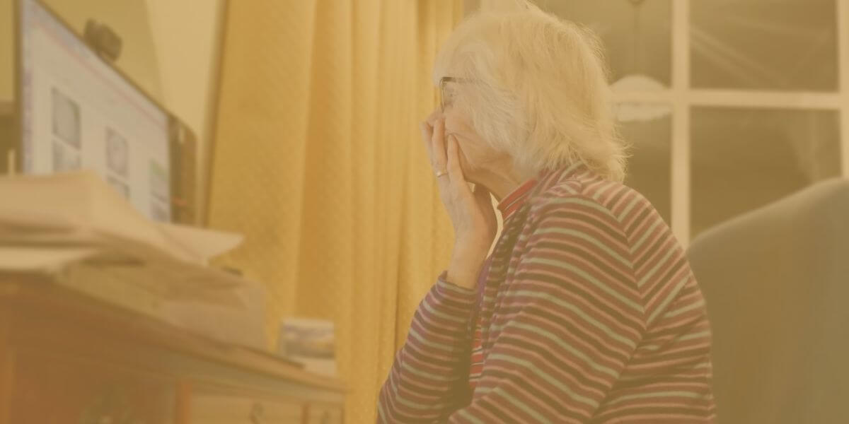 Elderly woman looks at computer screen at home
