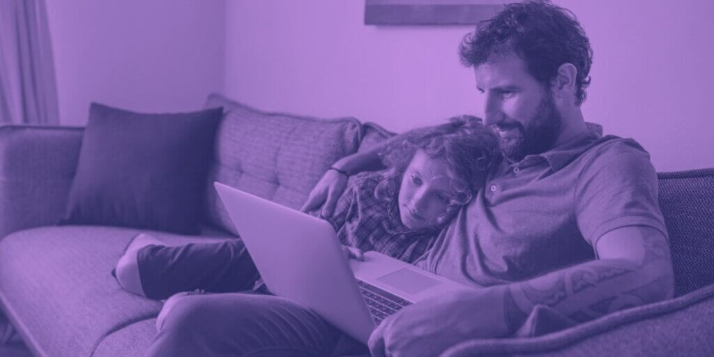 Man sits with child on couch looking at digital device