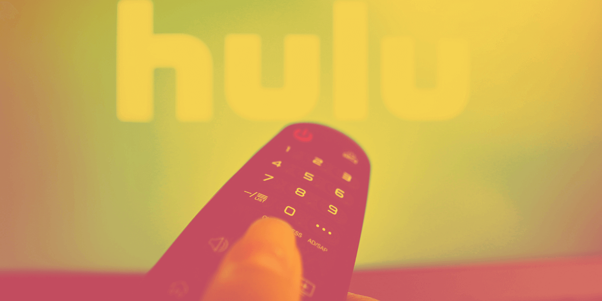 Remote control on hand with TV on with Hulu on the background