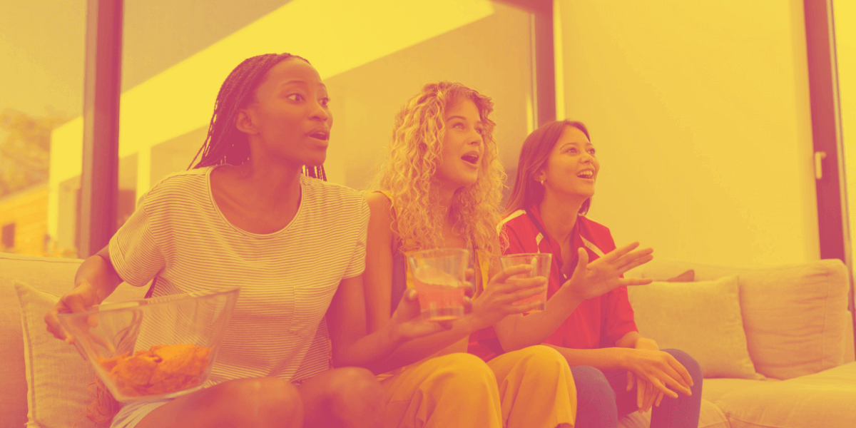 Girls watching TV while eating Doritos and having a cocktail