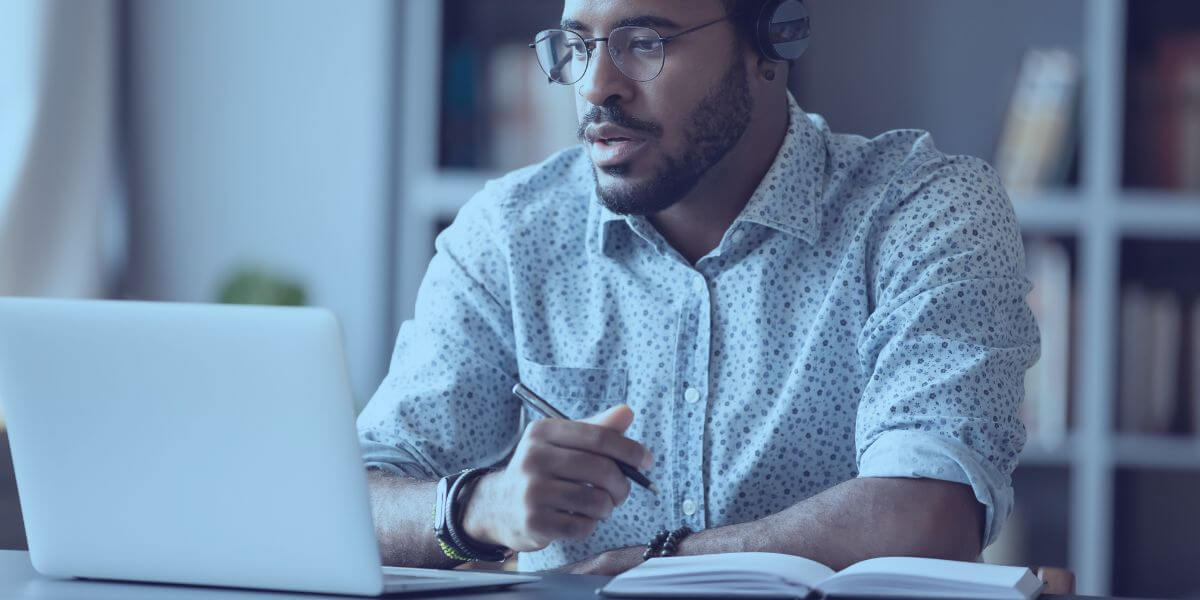 man using laptop for online learning and taking notes