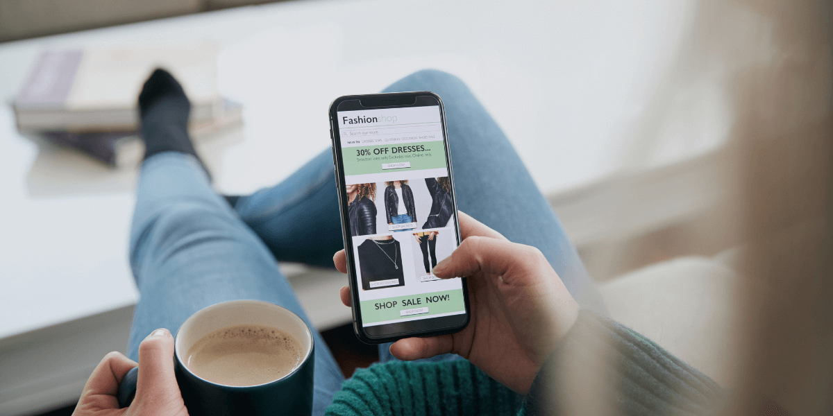 Person scrolling through shopping site while drinking coffee