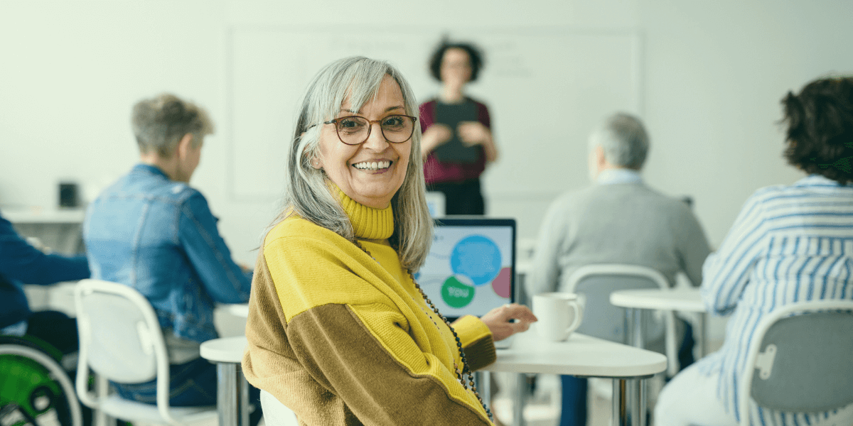 white haired woman smiling while in a class