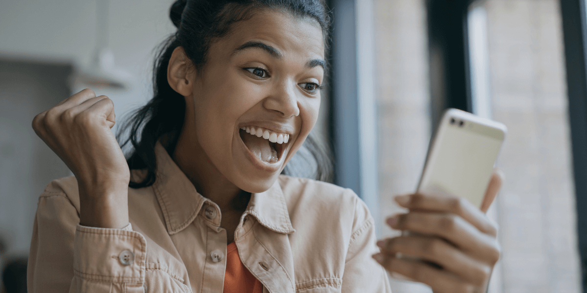 young woman smiling while looking at her smart phone