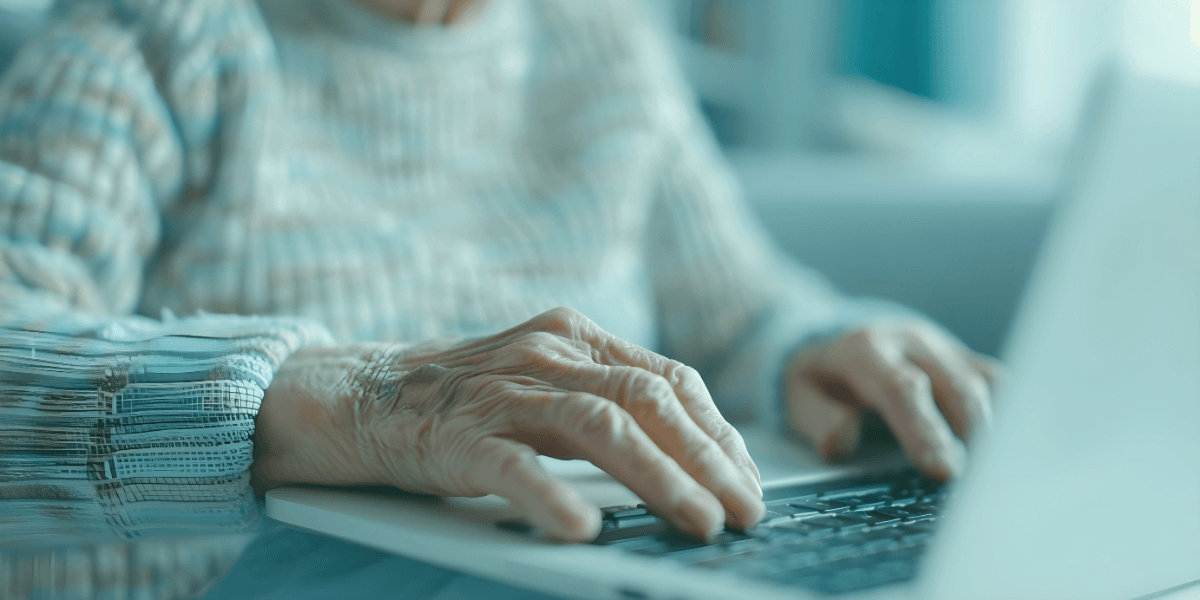 older person typing on a laptop