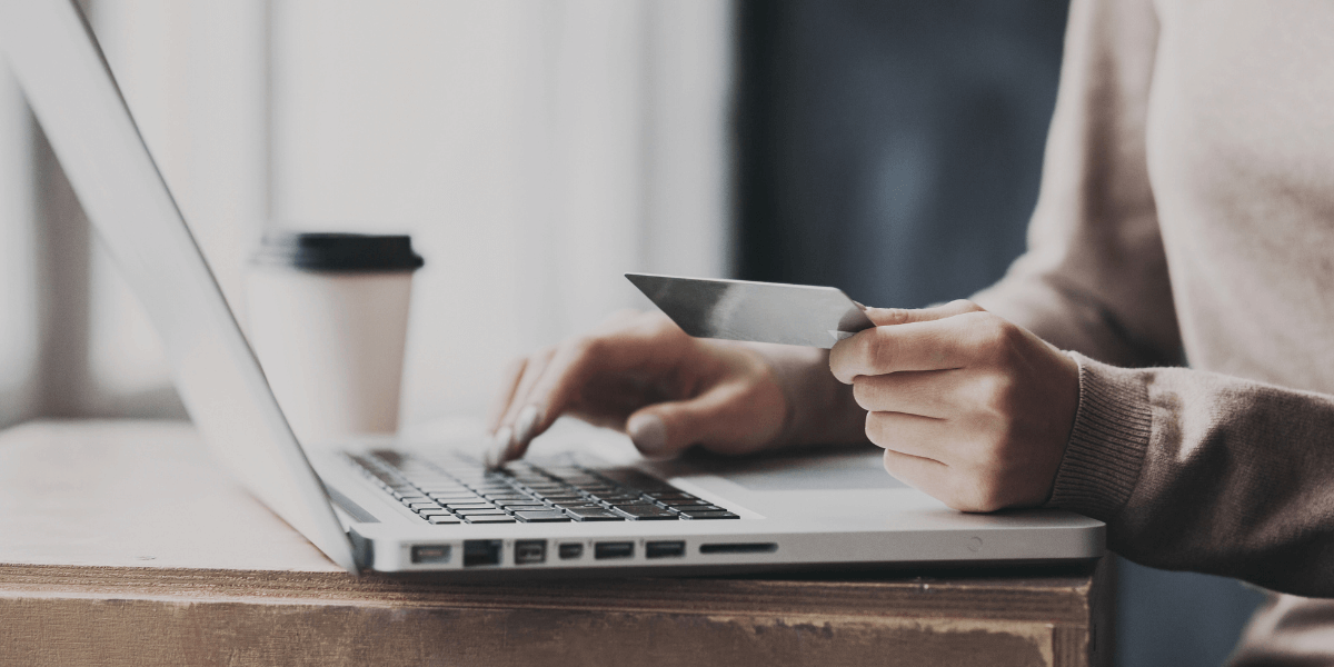 person holding a credit card while on their laptop