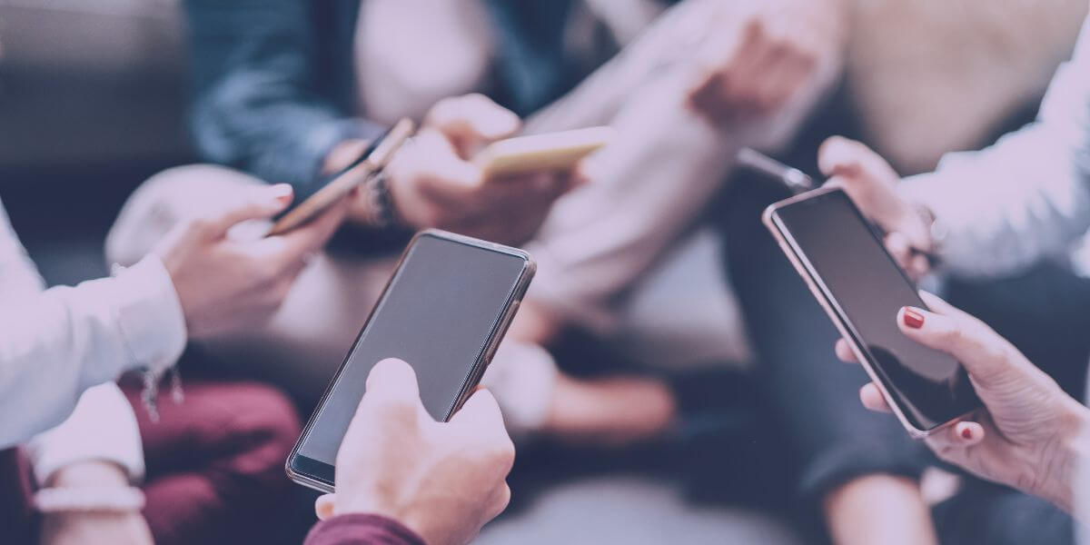 group standing in circle holding smartphones