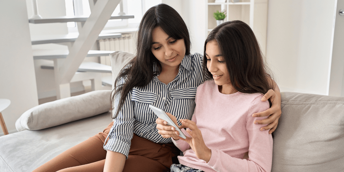 Young woman and a little girl looking at a phone together