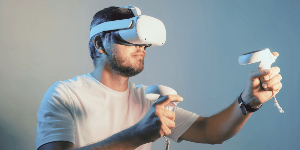 man wearing a VR headset while holding up both gaming controllers