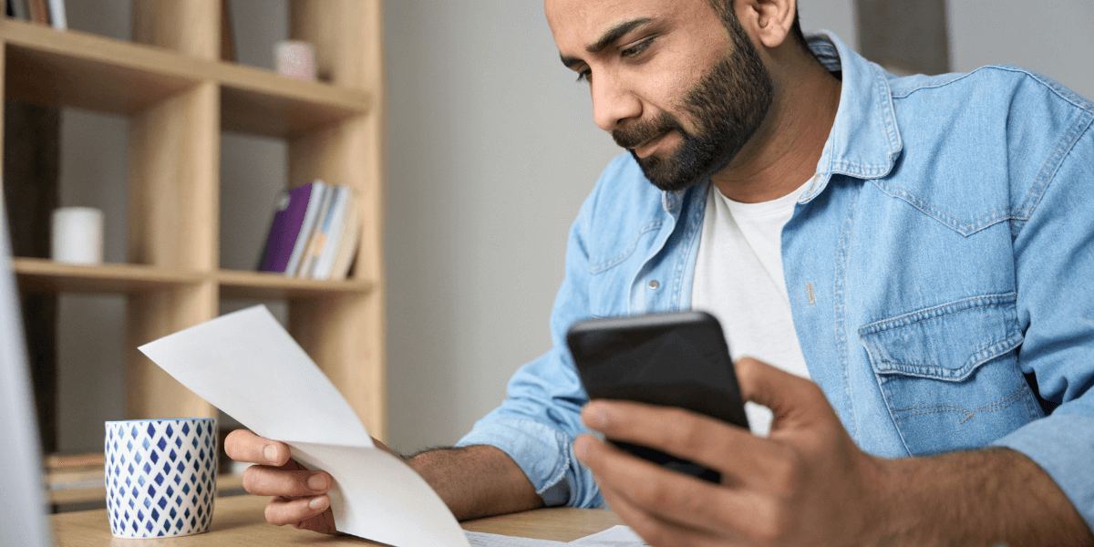 Man holding phone and phone bill