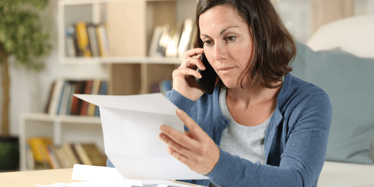 Woman looking frustrated on the phone looking at paper