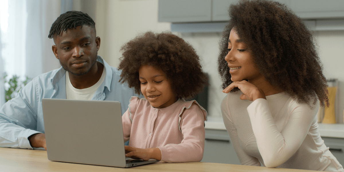 two parents with their young daughter looking at a laptop