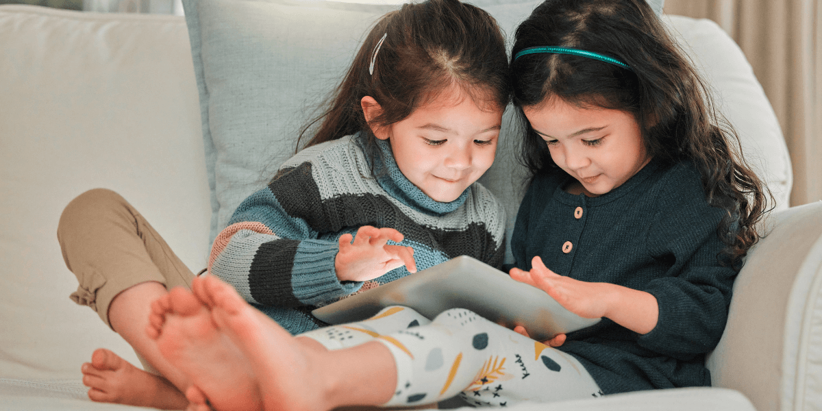 two young girls on a couch looking at an ipad