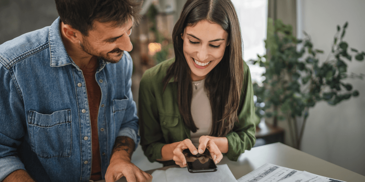 woman and man looking at phone over phone bills