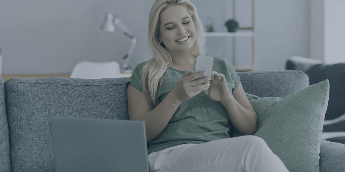 woman on her phone with her laptop open sitting next to her