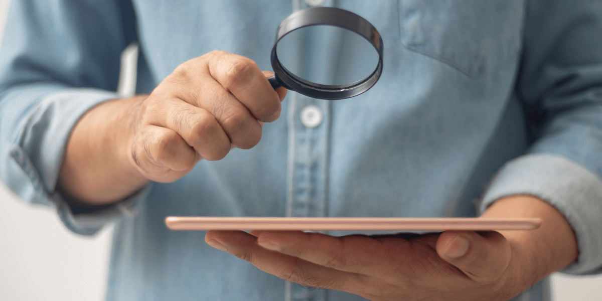 man holding a magnifying glass up to an ipad screen