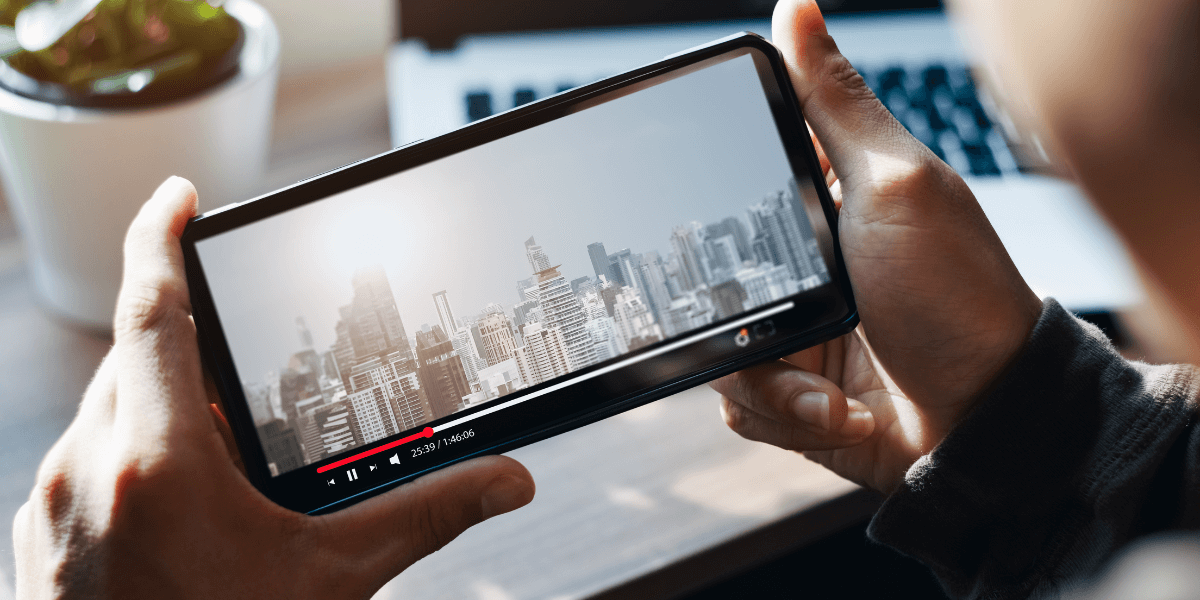 person holding a phone with a video of a city on the screen