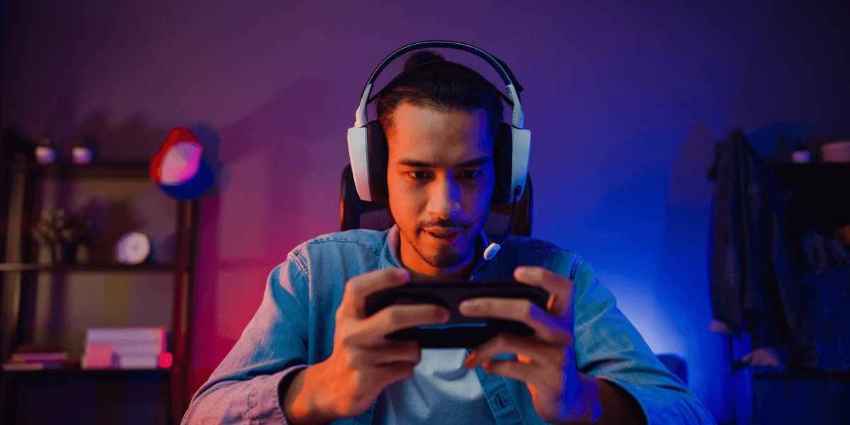 Guy with headset on playing a mobile game on his phone