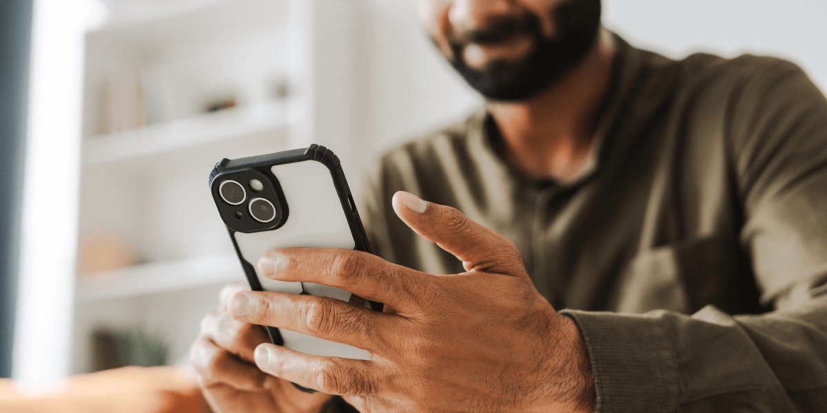 man smiling while holding a cell phone