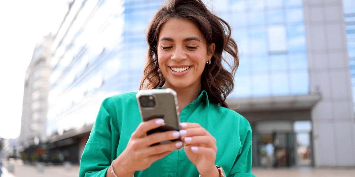 Woman in a green shirt smiling while holding a phone