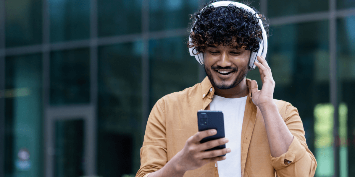 guy with headphones on looking at his cell phone