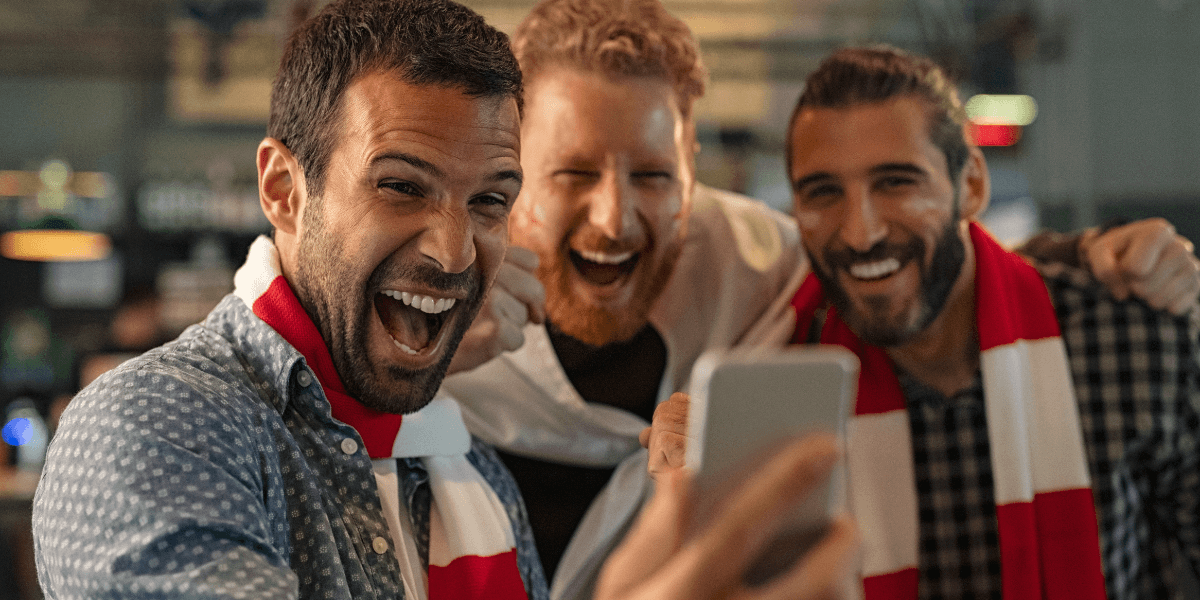3 men watching sports on a phone