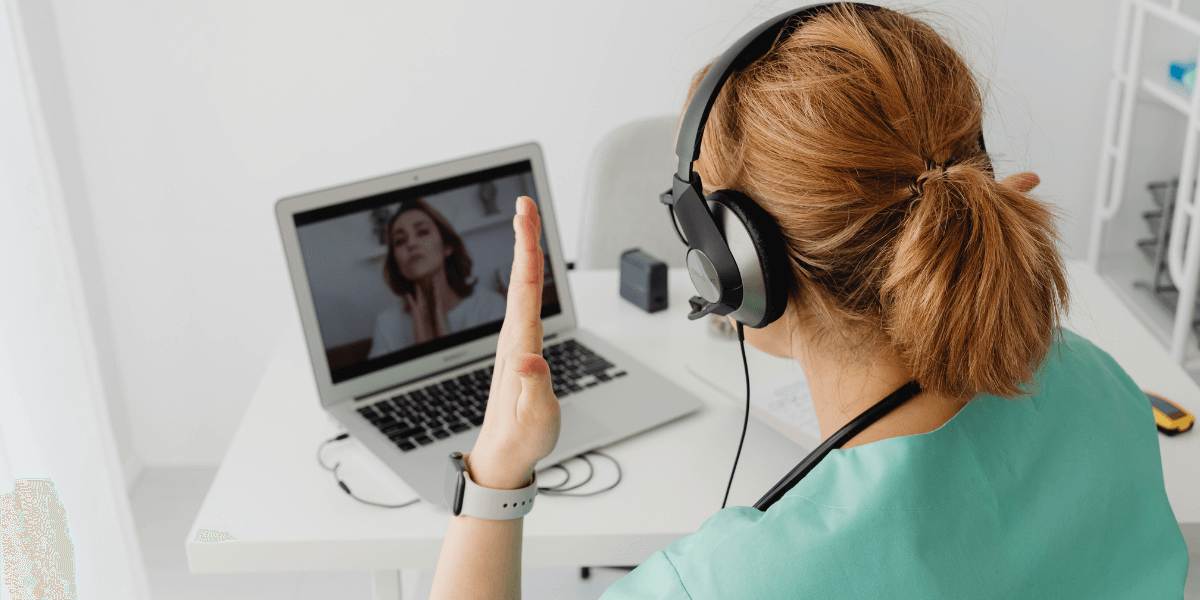 Woman with headphones on holding hands in frustration while looking at a laptop