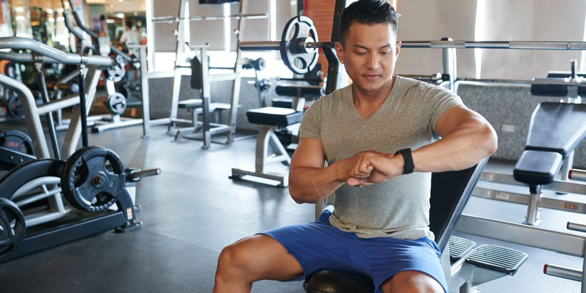 man in weight room looking at fitness tracker