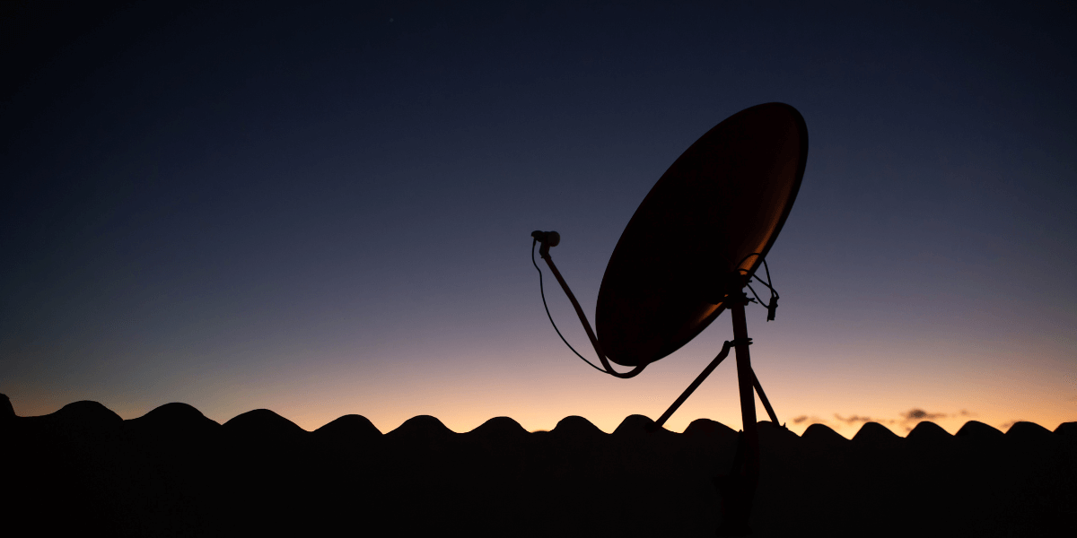 a satellite dish on top of a house at sunset