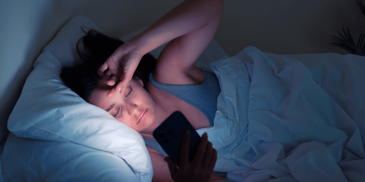 woman laying in bed on phone at night