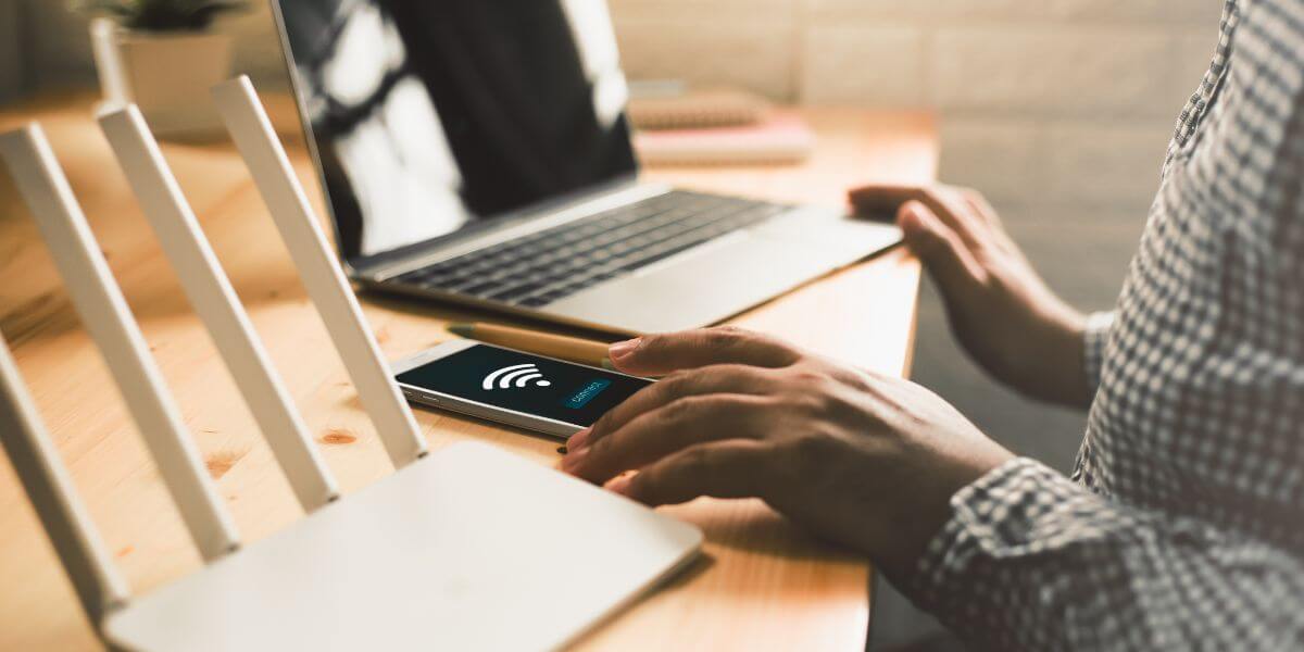 person at desk with router, phone, and laptop